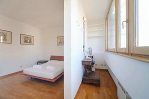 Une chambre à coucher avec un lit, une table de chevet, une lampe et une fenêtre.
