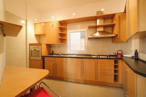A kitchen with wooden cabinets, a stove, a sink, and a window.
