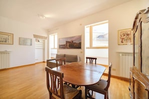 A dining area with a wooden table and chairs, a sofa, and artwork on the walls.