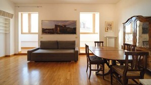 Een kamer met een bank, een eettafel, stoelen en kunst aan de muren.