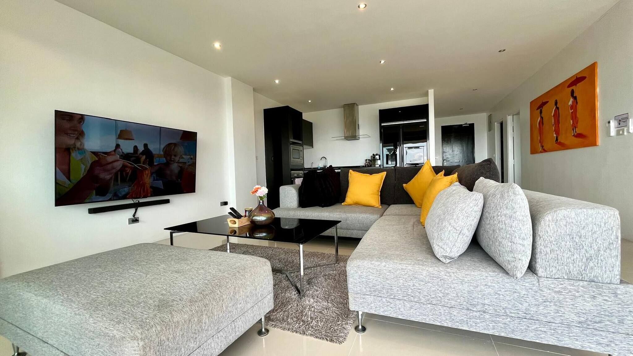 A modern living room with a grey sofa, a black coffee table, and a flat-screen TV.