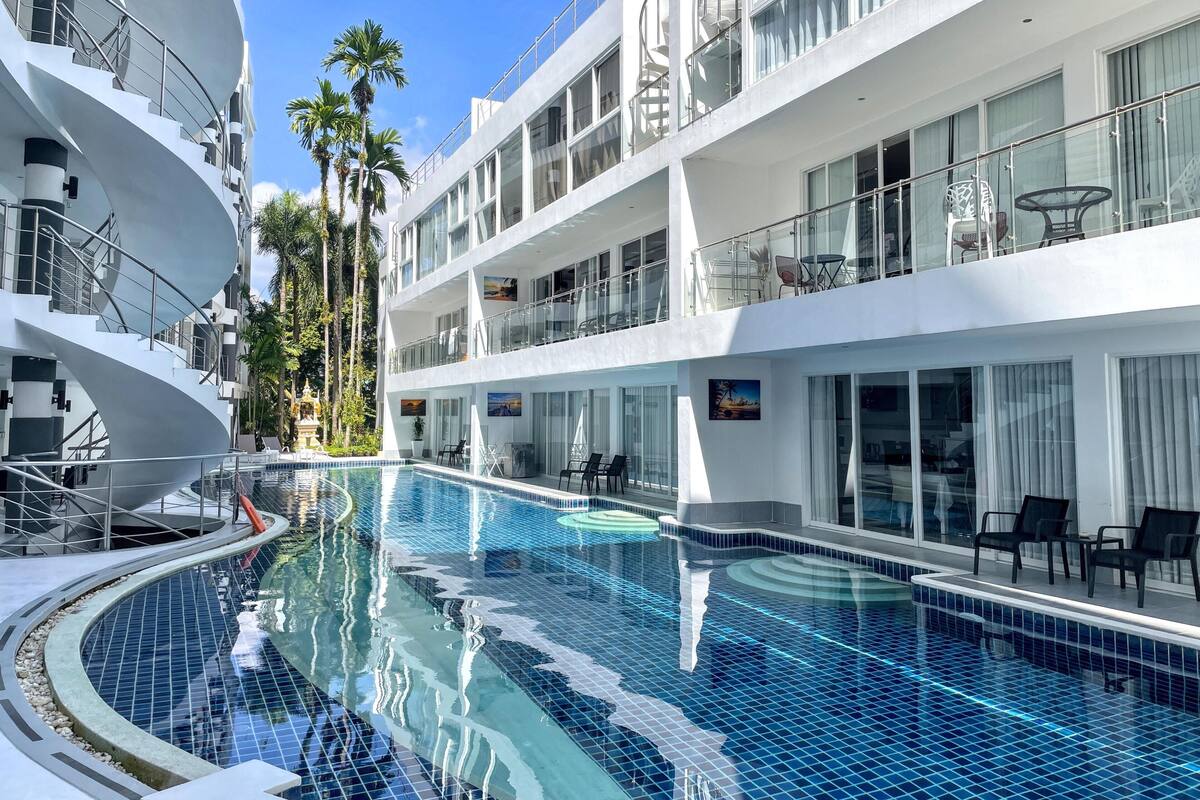 Ein Kreuzfahrtschiff mit Pool, mehreren Balkonen und Palmen.