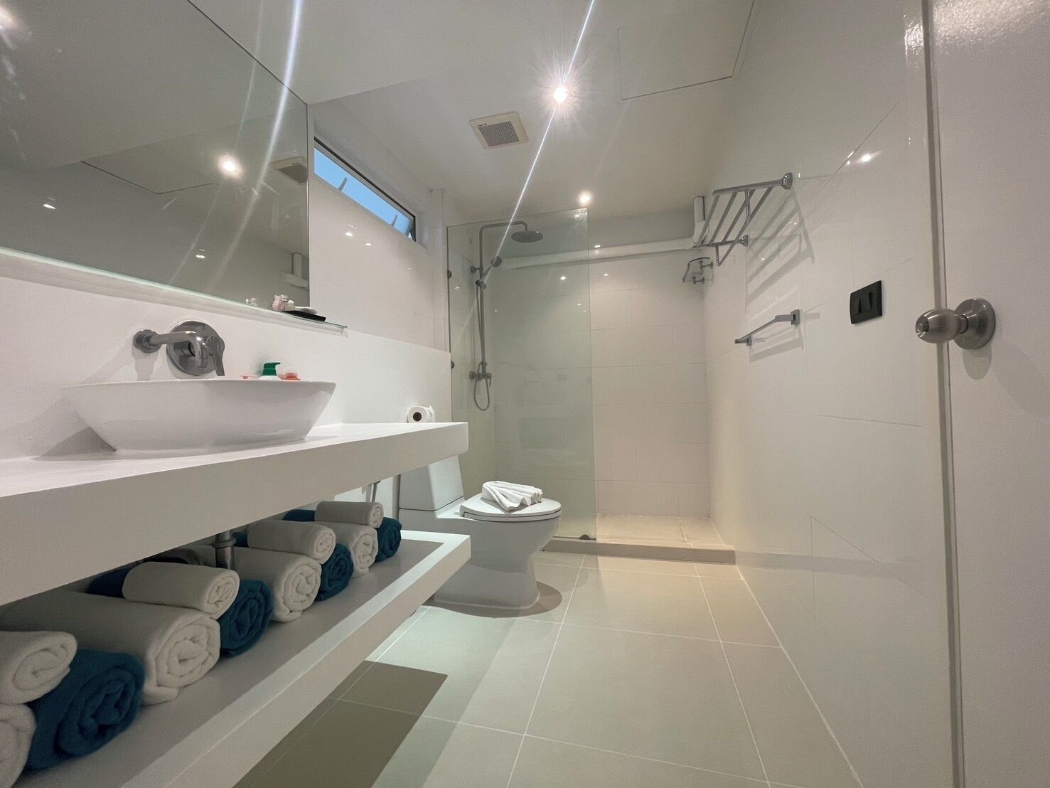 A modern bathroom with a white sink, mirror, and shower.