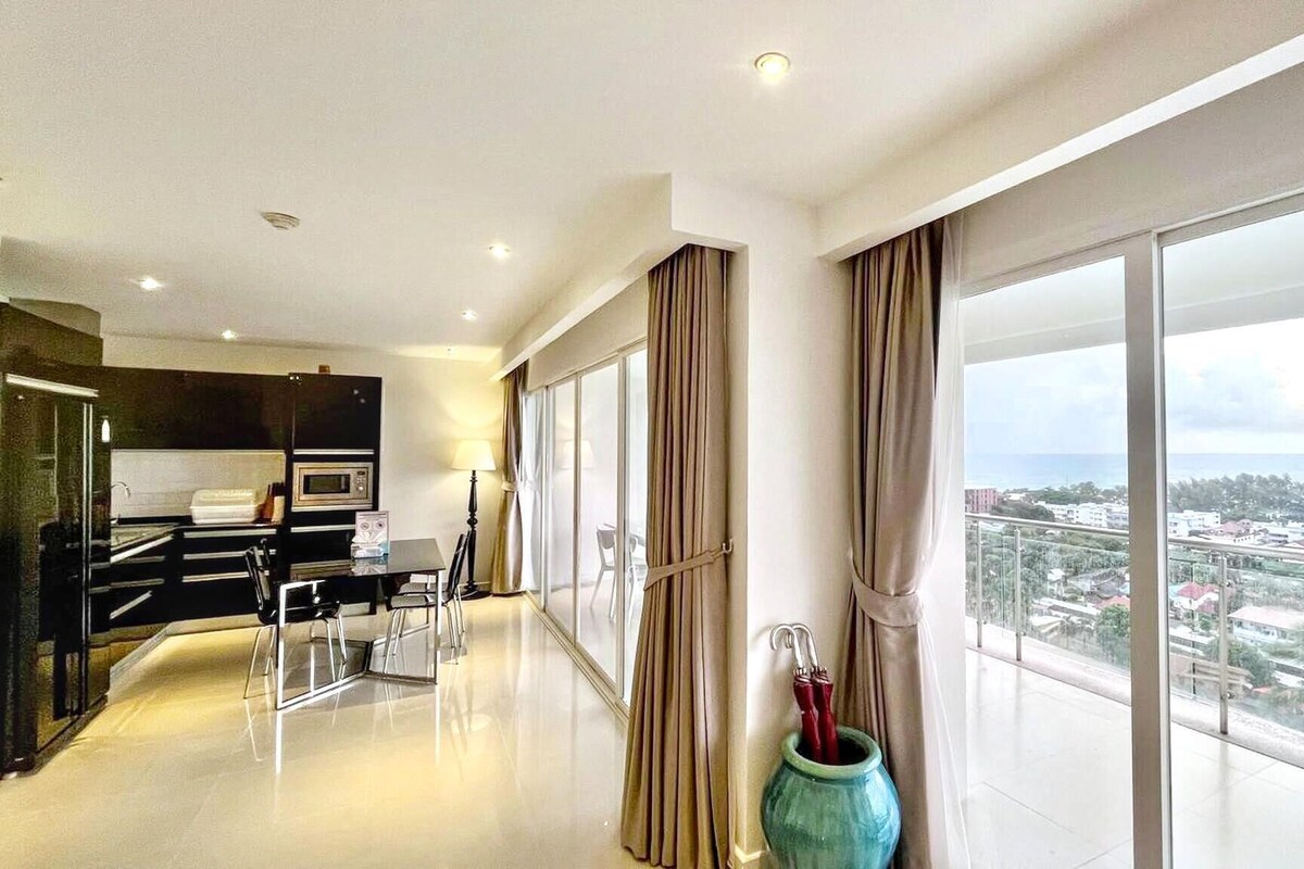 A modern hotel room with a balcony, a dining area, and a view of the city.