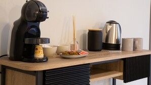 A kitchen counter with a coffee maker, a kettle, a plate of food, and a few mugs. - Malva Rooms (Agrigento)