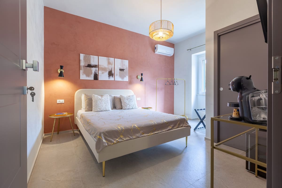 Une chambre moderne comprenant un lit, des tables de chevet, un climatiseur fixé au mur et un luminaire suspendu.
