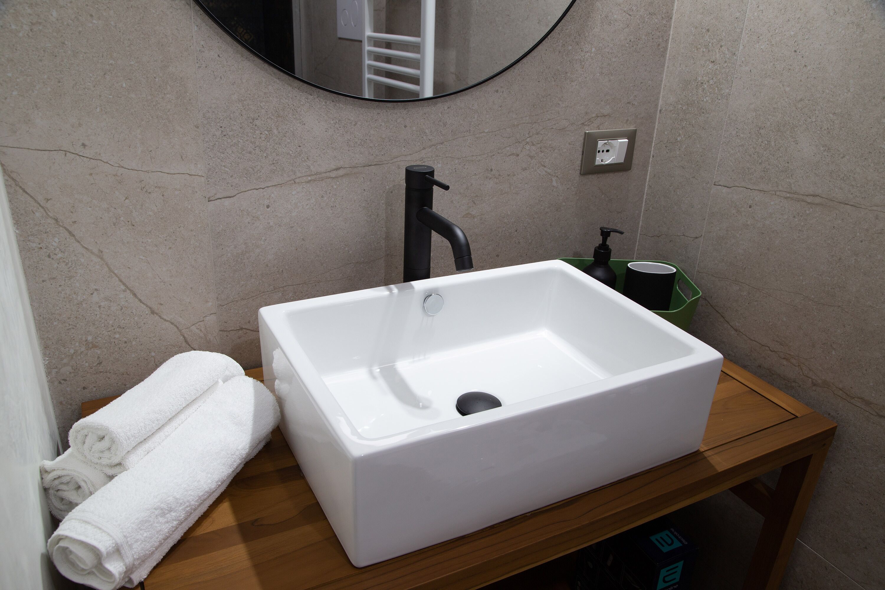 A bathroom with a white sink, a mirror, and a wooden vanity.
