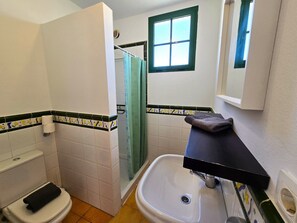 Een badkamer met toilet, wastafel, douche en een raam.