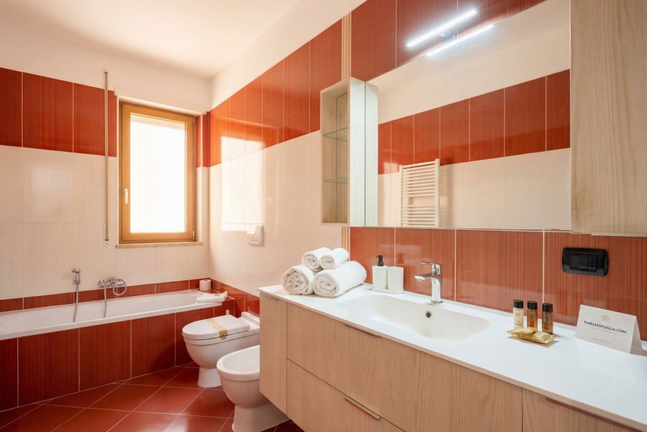 A modern bathroom with a bathtub, toilet, sink, and a large mirror.
