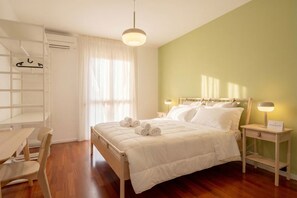 A neatly arranged bedroom with a bed, bedside tables, a chair, a desk, and a wardrobe.