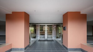 Un vestíbulo amplio con suelo de baldosas, puertas de cristal y paredes anaranjadas.