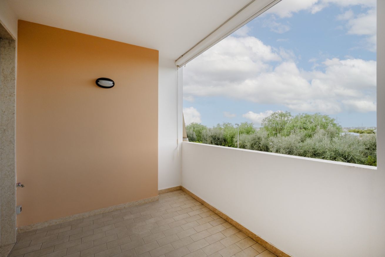 Un balcon donnant sur une végétation luxuriante et un ciel nuageux.