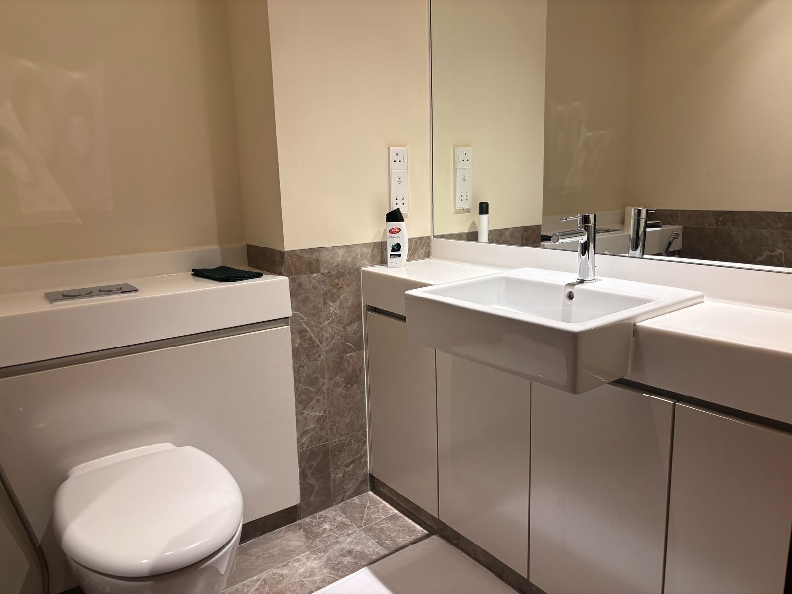 A modern bathroom with a white toilet, a sink, and a mirror.