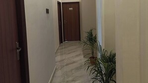 A hallway with marble flooring, wooden doors, and potted plants. - A28 Orange Bricks (Kolkata)