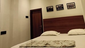 A bedroom with a bed, a wooden headboard, and three framed pictures on the wall. - A28 Orange Bricks (Kolkata)