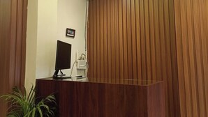 A reception area with a wooden reception desk, a flat-screen monitor, and a ceiling-mounted air conditioning unit. - A28 Orange Bricks (Kolkata)