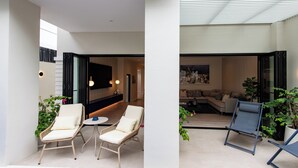 A modern interior with a seating area featuring two lounge chairs and a small table, a living room with a sofa and a coffee table, and a kitchen area with a dining table. - Palazzo 126 • Luxury 5BR Pool Villa in Patong (Patong, Kathu)