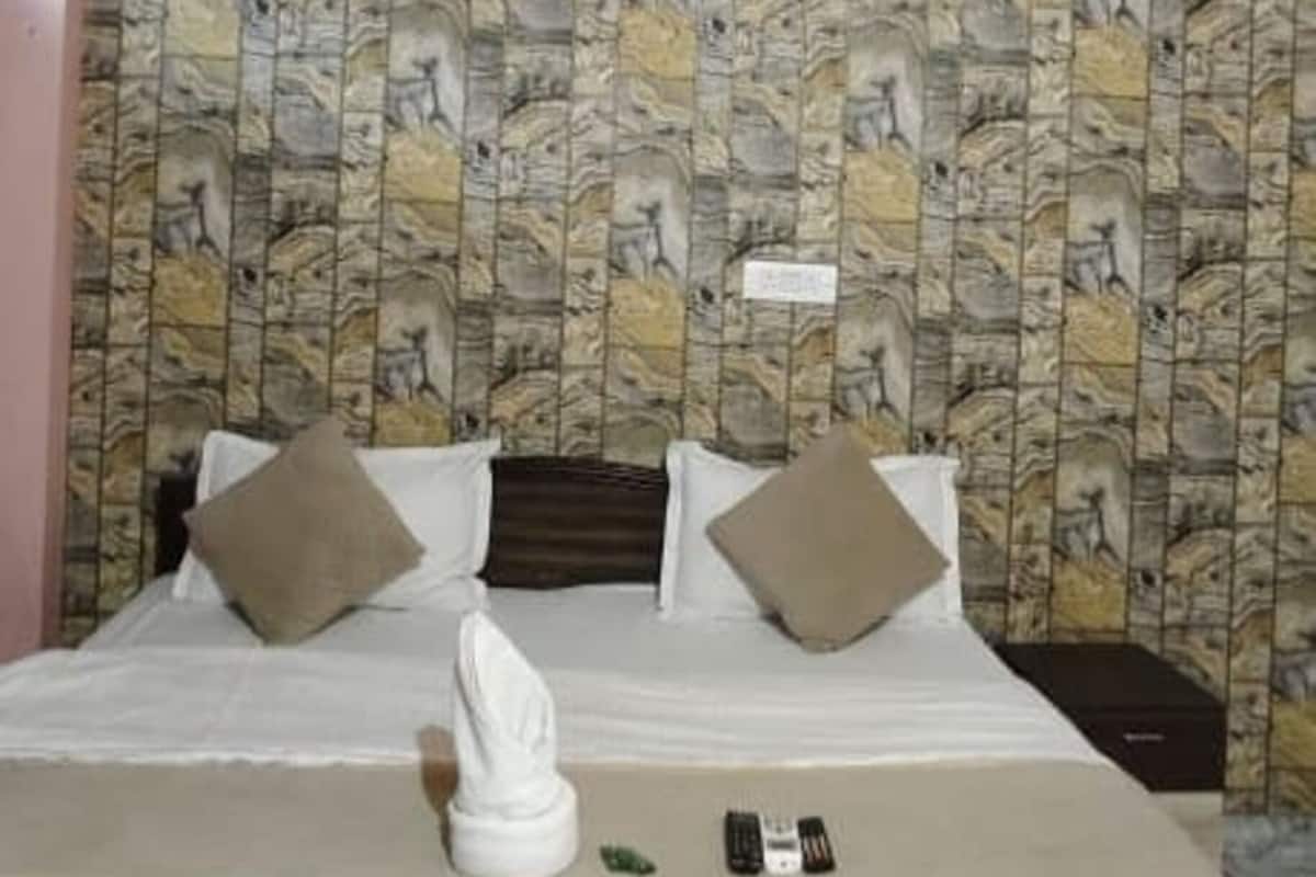 Een hotelkamer met een bed, een plafondventilator en behang met een patroon.