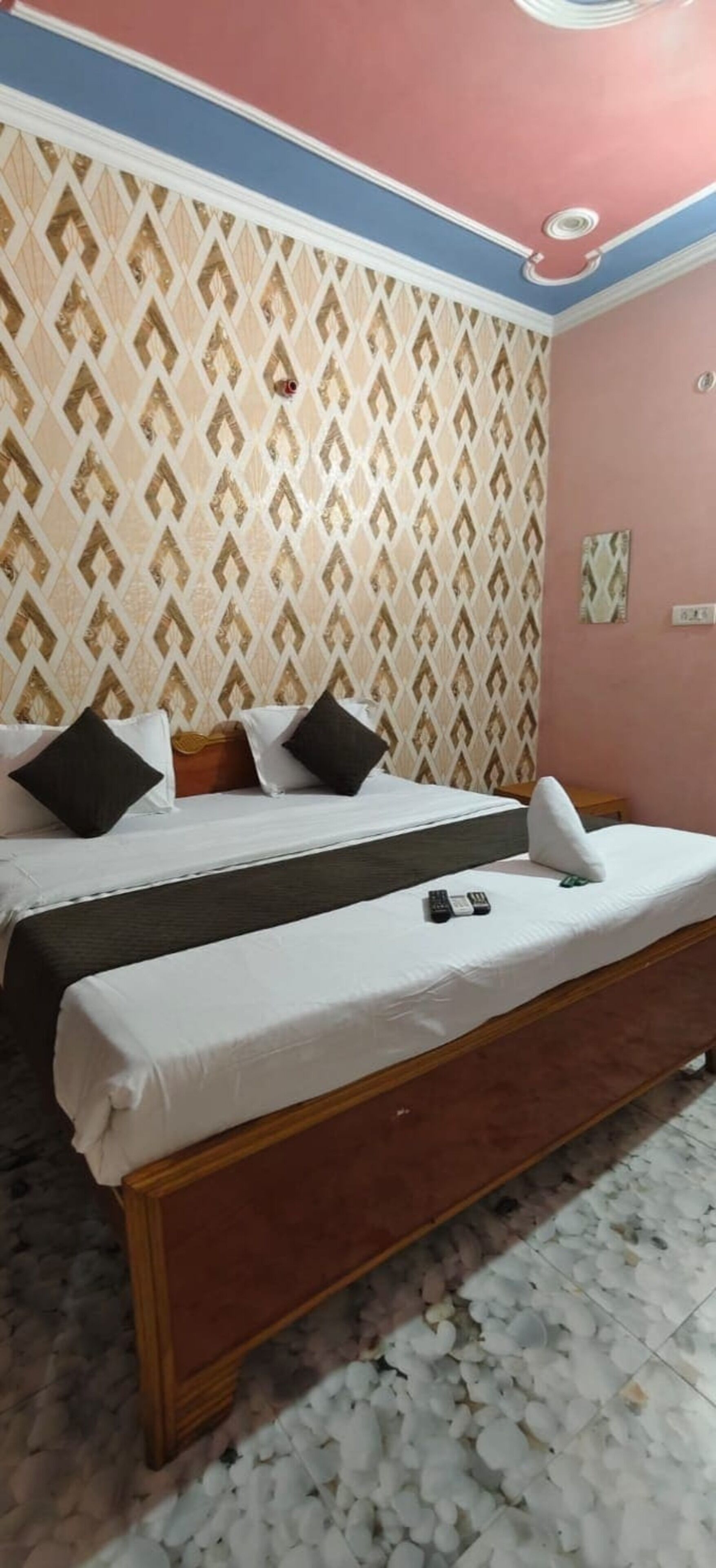Una camera da letto con un letto, cuscini e un telecomando sul letto.