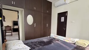 Un dormitorio con una cama grande, un armario de madera oscura, ventilador de techo y aire acondicionado.