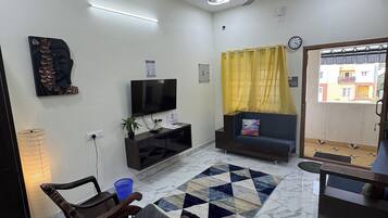 A living room with a TV, sofa, and a decorative wall piece.