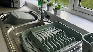 Eine Küche mit eingebautem Geschirrspüler, einer Spüle mit zwei Becken und einem Fenster mit Blick ins Grüne.
