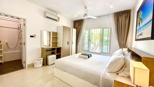 Quarto de hotel com cama, guarda-roupa, casa de banho e janela com cortinas.