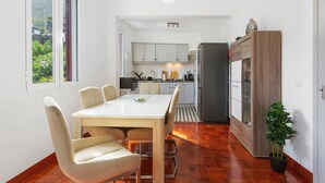 Una cocina moderna con armarios blancos, una mesa de comedor con sillas y una planta en maceta.
