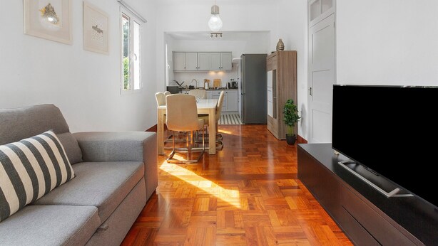 Una sala de estar moderna con sofá, comedor, cocina y televisión.
