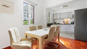 Una cocina moderna con armarios blancos, un refrigerador y un comedor con mesa y sillas.