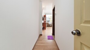 Un couloir étroit, doté d’un plancher en bois, mène à une cuisine.