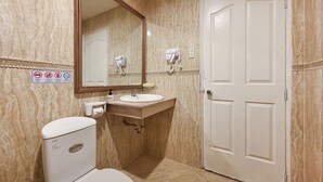 Une salle de bain avec des toilettes, un lavabo et un miroir. Il y a des panneaux sur le mur et une porte sur la droite.
