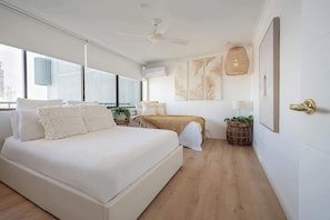 Une chambre moderne avec un grand lit, un ventilateur de plafond et une vue sur la ville.