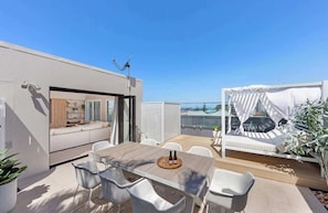 A rooftop terrace with a dining area, a seating area with a canopy, and a view of the city skyline. - Tide by Khove (Miami)
