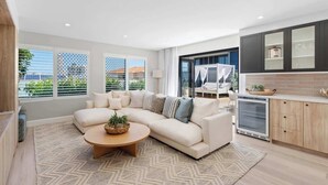 Ein modernes Wohnzimmer mit einem Ecksofa, einem runden Couchtisch und Blick ins Freie durch große Fenster.