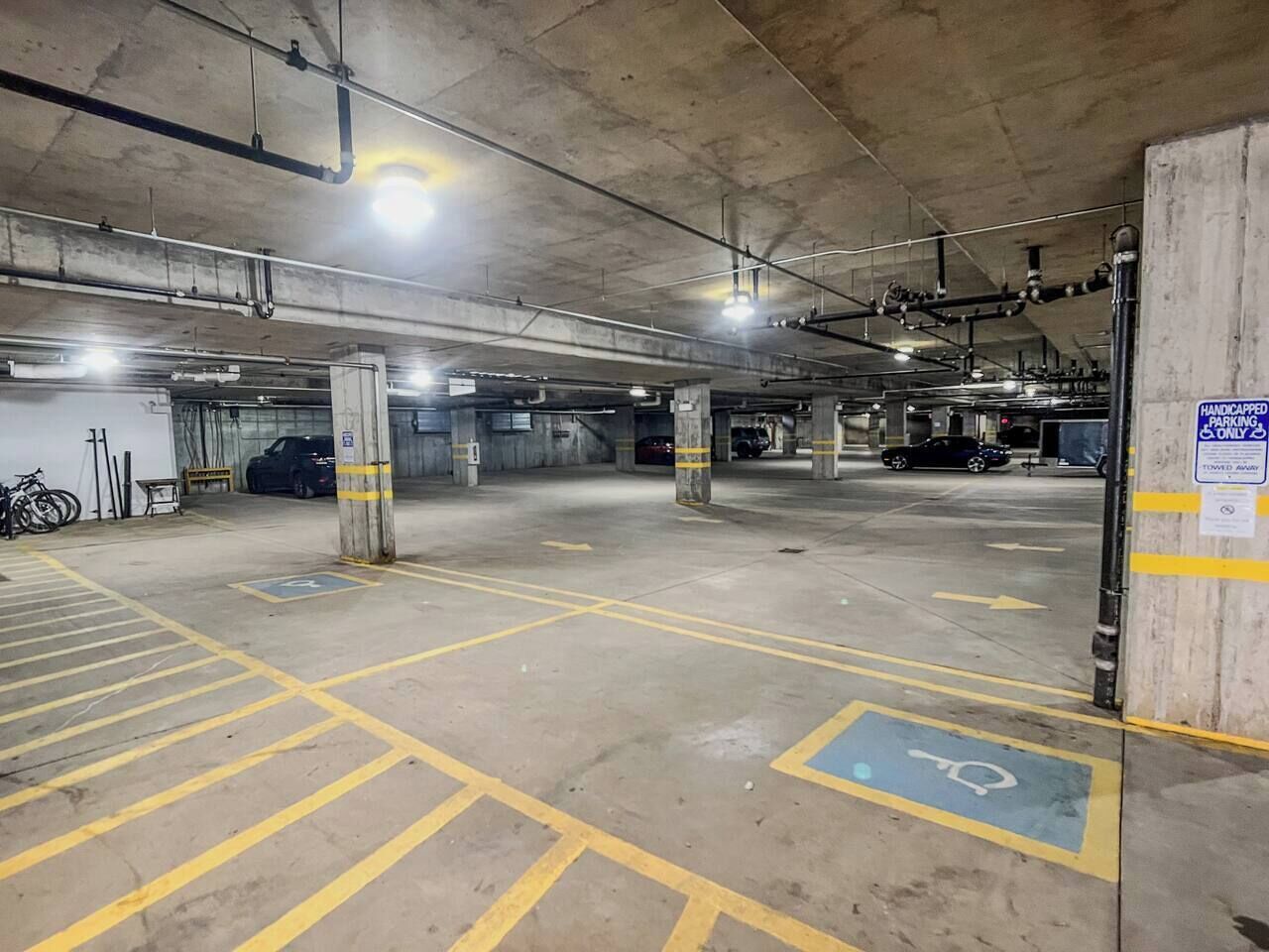 Eine mehrstöckige Parkgarage mit deutlich gekennzeichneten Behindertenparkplätzen und Pfeilen zur Orientierung auf dem Boden.
