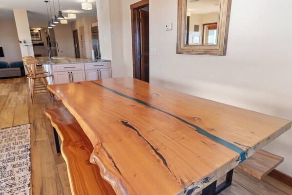 Una cocina amplia con una isla grande de madera, armarios blancos y una lámpara colgante moderna.
