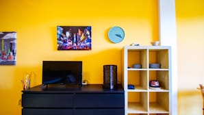 A room with a black desk, a television, a clock, and a shelf with decorative items. - Suite Panorama Puegnago (Puegnago del Garda)