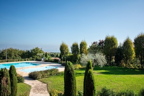 A swimming pool surrounded by well-maintained lawns and tall, slender trees. - Suite Panorama Puegnago (Puegnago del Garda)