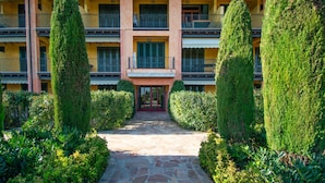 A multi-story building with a central entrance, surrounded by well-maintained hedges and a stone pathway. - Suite Panorama Puegnago (Puegnago del Garda)