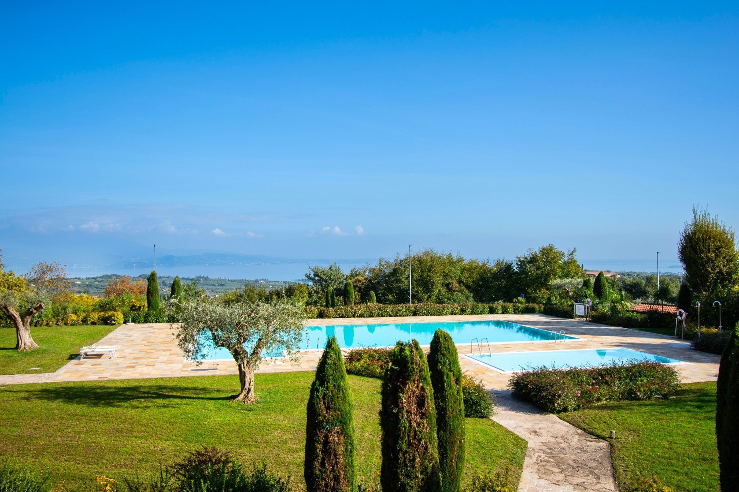 A swimming pool surrounded by a well-maintained garden with a clear view of the landscape.