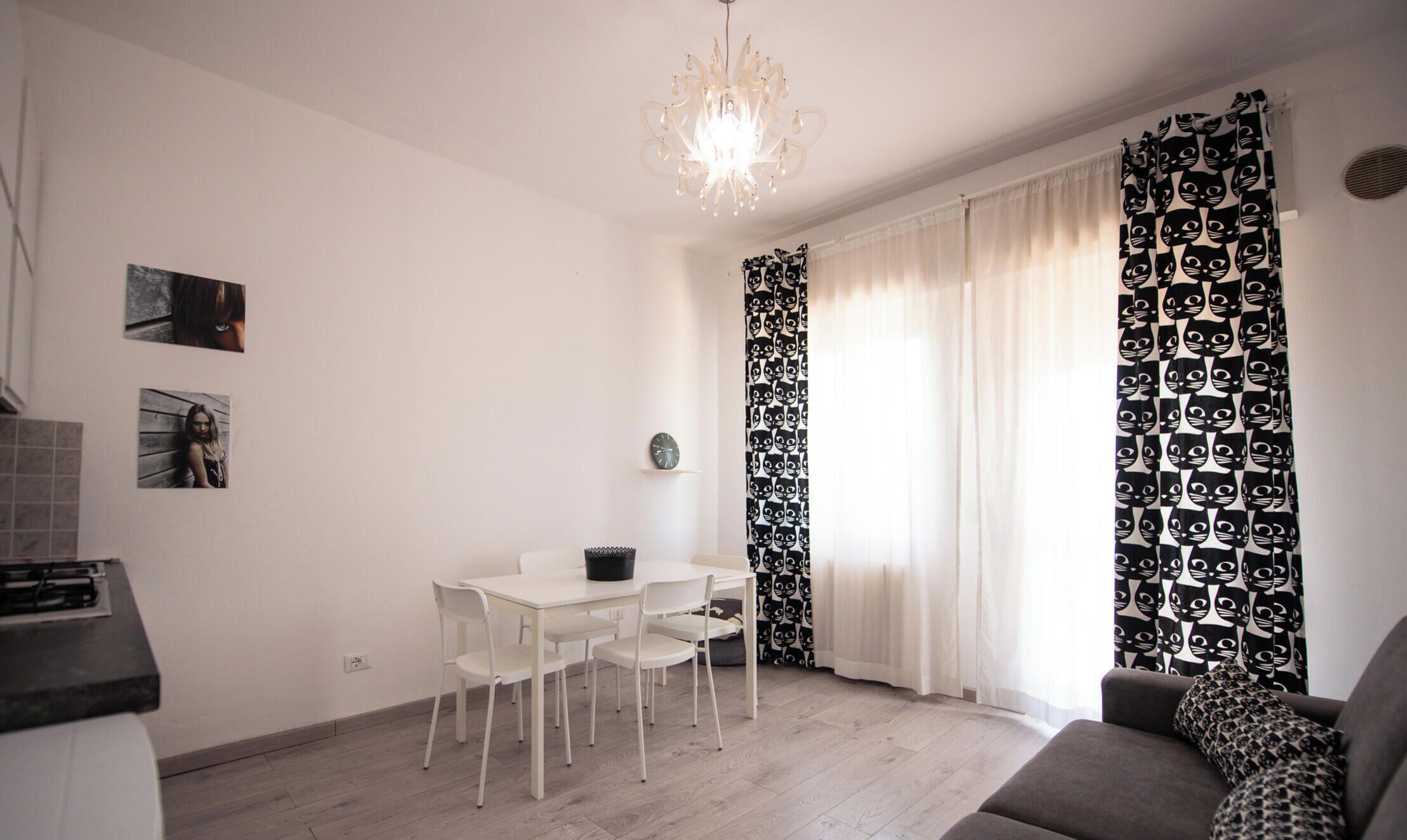 A modern living room with a dining area, a chandelier, and patterned curtains.