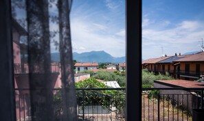 Un balcon donnant sur un quartier résidentiel, avec des maisons et des montagnes en arrière-plan.
