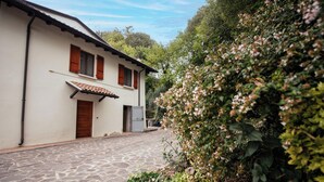A stone-paved courtyard with a white building featuring wooden shutters and a tiled roof. - Casa Reale in Volta Mantovana (Volta Mantovana)