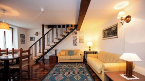 A living room with a wooden staircase, a sofa, a coffee table, and a patterned rug. - Casa Reale in Volta Mantovana (Volta Mantovana)