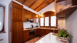A kitchen with wooden cabinets, a stove, microwave, and a sink. - Casa Reale in Volta Mantovana (Volta Mantovana)