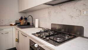 Una cocina moderna con armarios blancos, estufa de acero inoxidable y salpicadero de mármol.