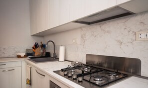 Una cocina moderna con armarios blancos, estufa de acero inoxidable y salpicadero de mármol.