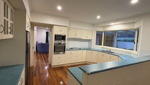 Una cocina moderna con armarios blancos, horno empotrado, microondas y estufa a gas.
