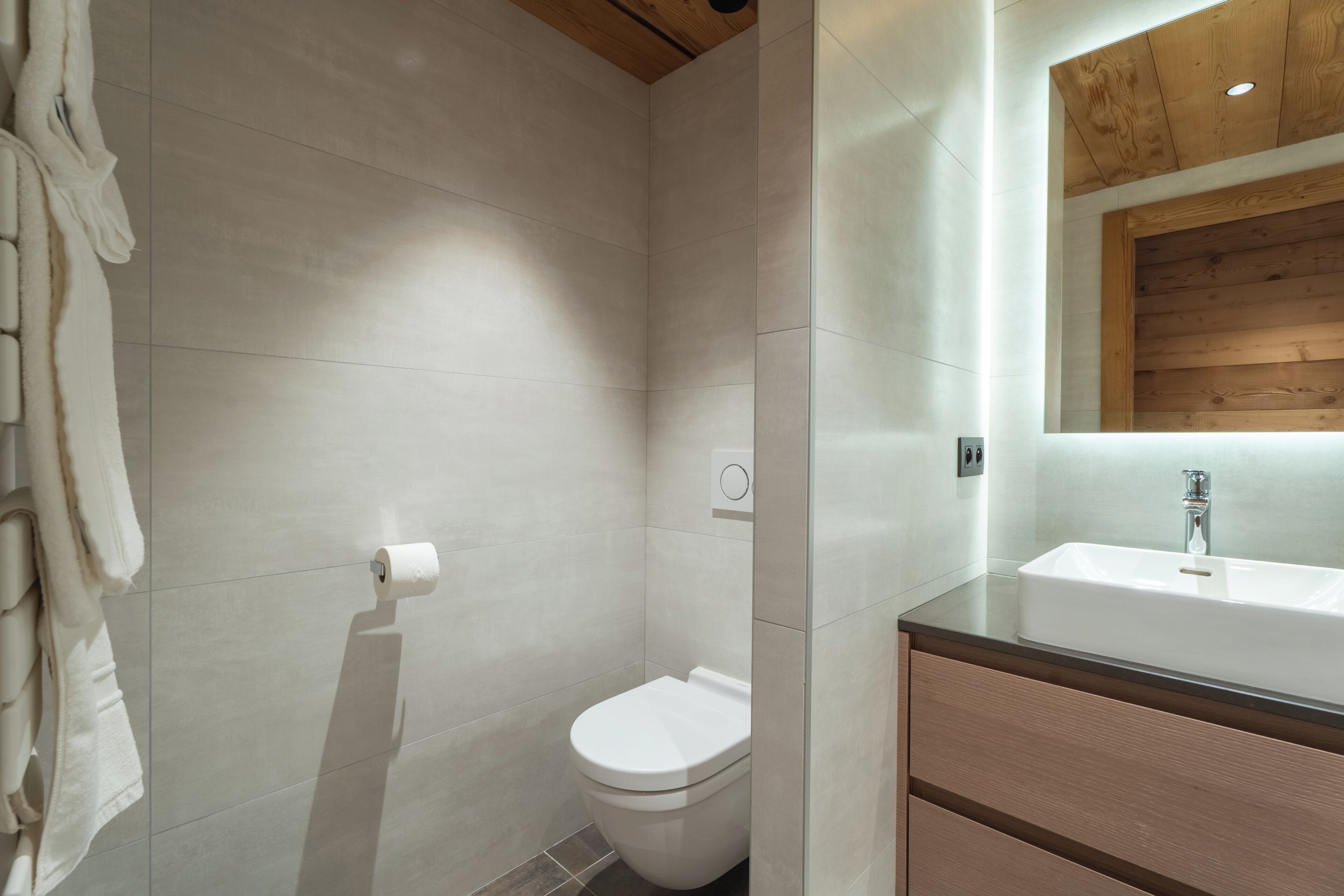 A modern bathroom with a toilet, a sink, and a towel rack.